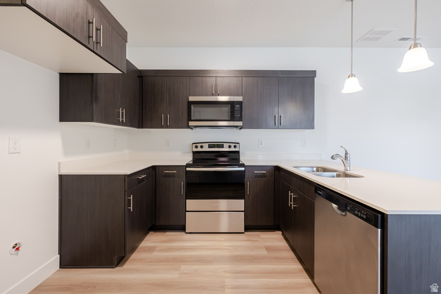693 West 4500th South, Unit O101 Mapleton, UT 84664 - Photo 11 of 16 Kitchen featuring dark wood finish cabinets, a peninsula, stainless steel appliances, light wood-style flooring, and pendant lighting