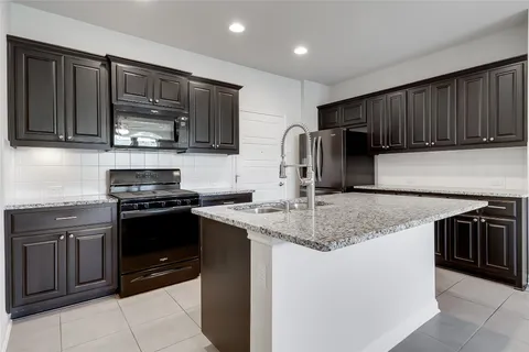 a kitchen with stainless steel appliances granite countertop wooden cabinets a stove a sink and a oven