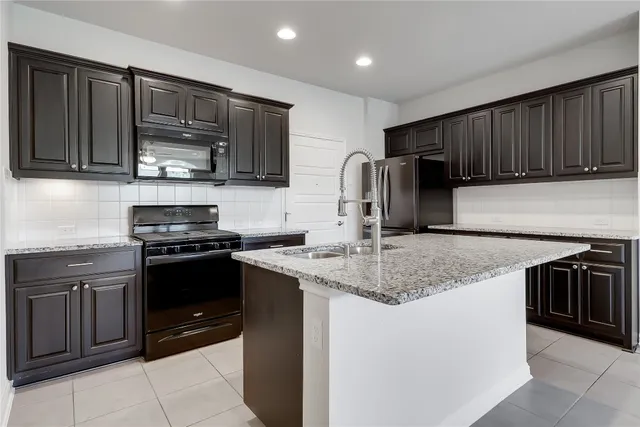 a kitchen with stainless steel appliances granite countertop wooden cabinets a stove a sink and a oven