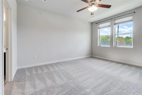 an empty room with chandelier fan and windows