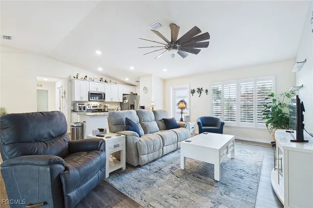 a living room with furniture kitchen view and a large window