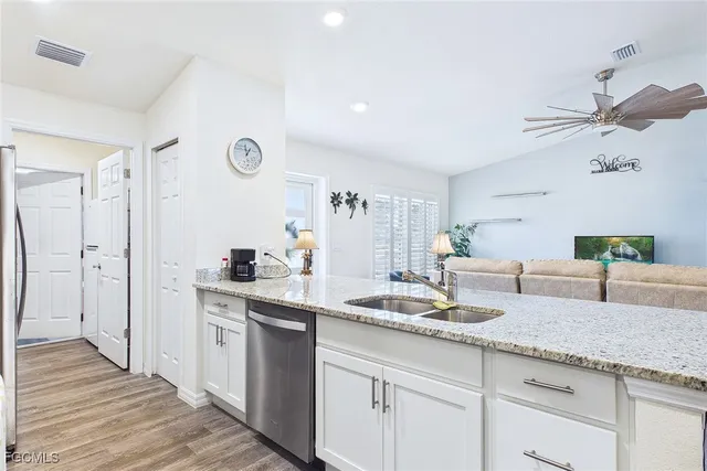 a kitchen with granite countertop a sink white cabinets and stainless steel appliances