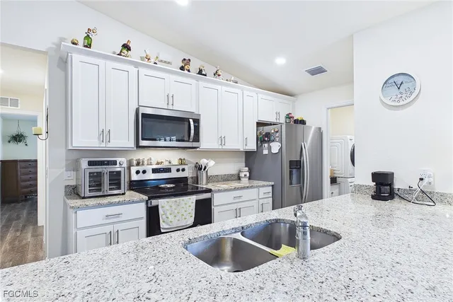 a kitchen with stainless steel appliances granite countertop a sink refrigerator stove and microwave