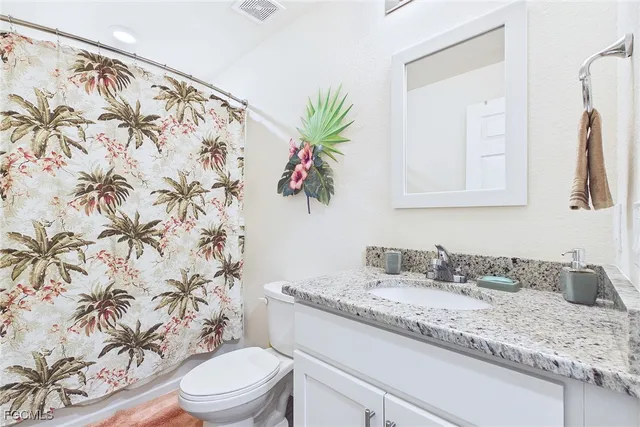 a bathroom with a granite countertop sink a toilet and a mirror