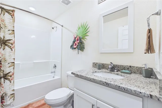 a bathroom with a granite countertop sink a toilet a mirror a vanity a shower and bathtub