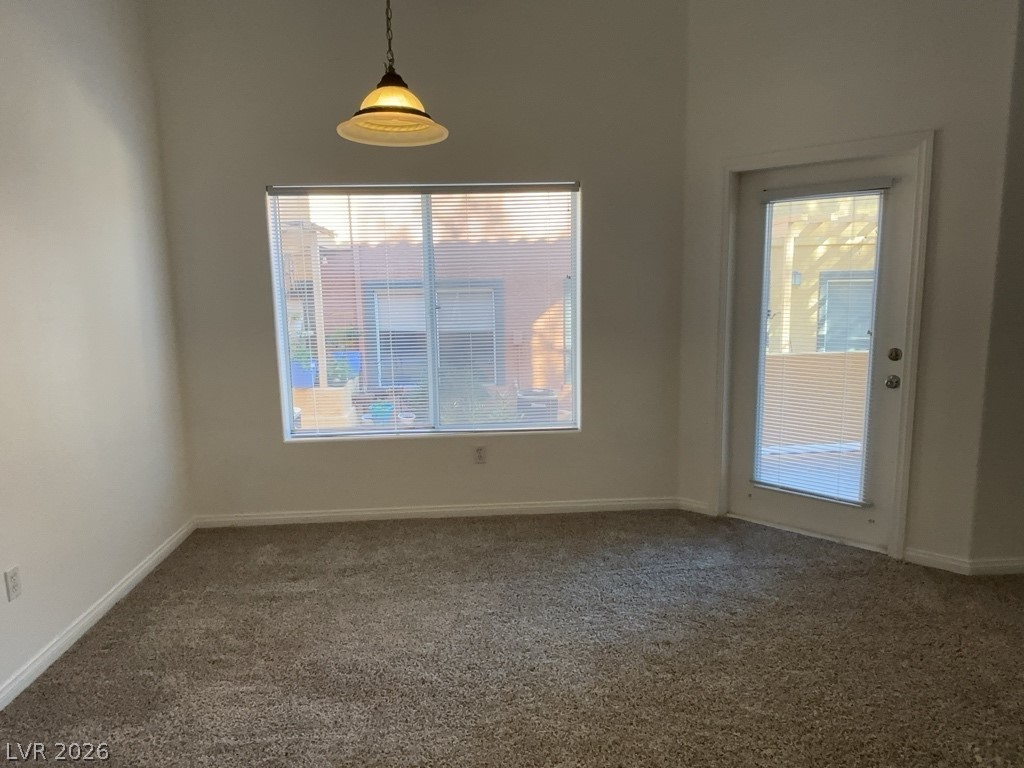 4915 East Russell Road, Unit 142 Las Vegas, NV 89120 - Photo 3 of 10 A spacious room featuring a light fixture, a window, and a door, all complemented by comfortable carpeting.