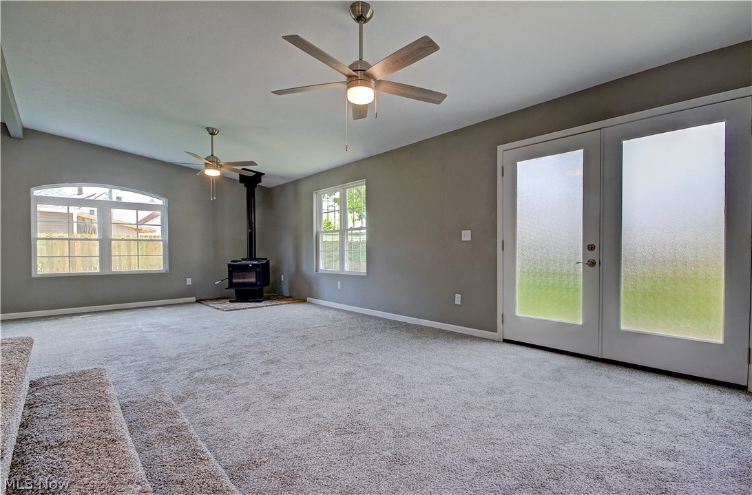 14507 Glencliffe Road Cleveland, OH 44111 - Photo 17 of 31 Unfurnished living room with french doors, carpet flooring, and a wood stove