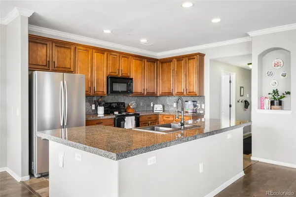 a kitchen with stainless steel appliances granite countertop a refrigerator a stove top oven a sink and dishwasher