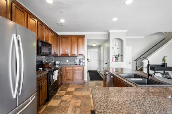 a kitchen with stainless steel appliances granite countertop a refrigerator a stove and a sink