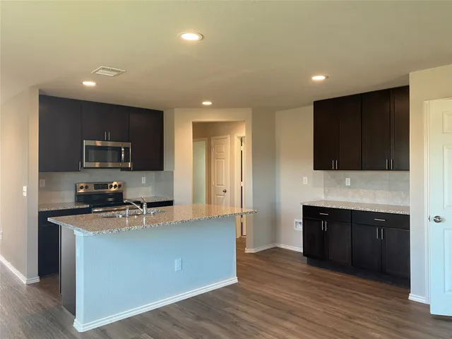 a kitchen with stainless steel appliances granite countertop a stove a sink and a refrigerator