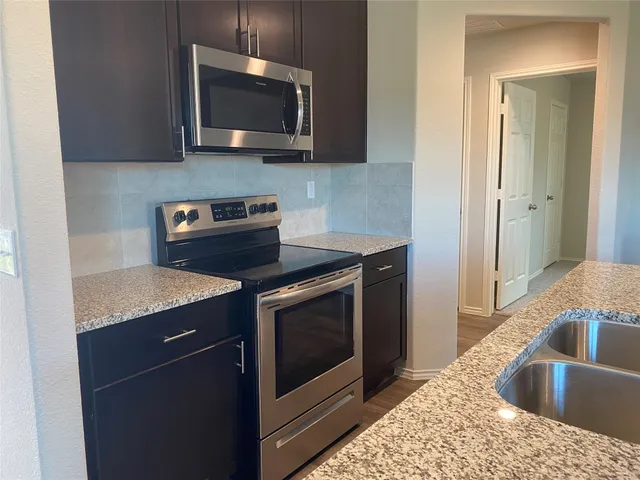 a kitchen with granite countertop a sink and a stove top oven