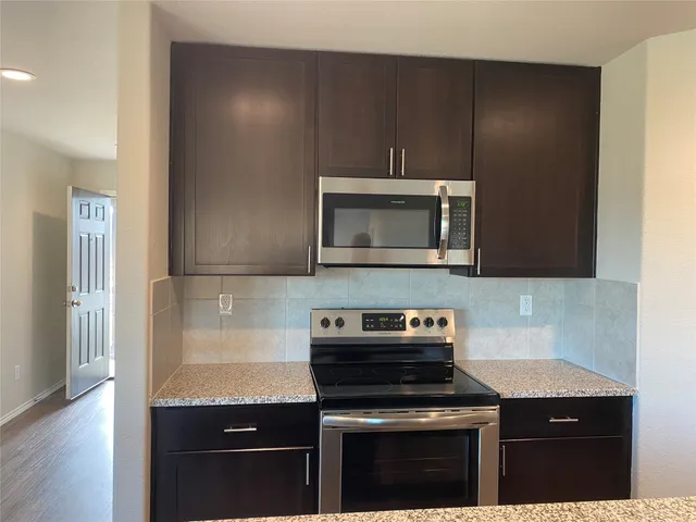 a kitchen with granite countertop a stove and a microwave
