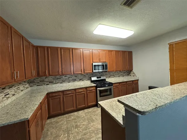 a kitchen with stainless steel appliances granite countertop wooden cabinets a stove and a sink