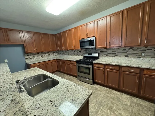 a kitchen with stainless steel appliances granite countertop a sink stove and microwave