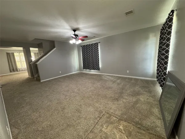 an empty room with windows and ceiling fan