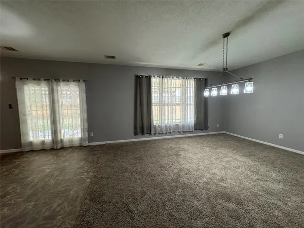 an empty room with windows and chandelier