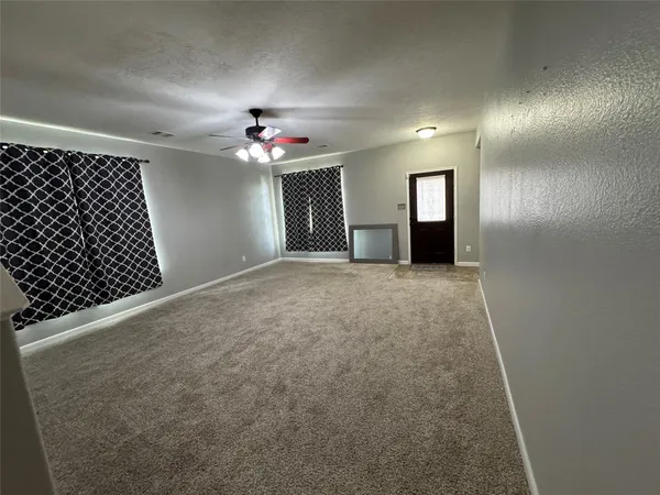 wooden floor in an empty room with a chandelier fan