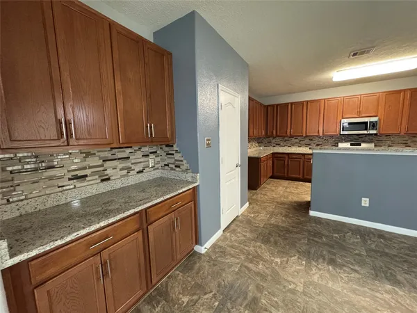 a kitchen with stainless steel appliances granite countertop a stove a sink and a refrigerator with wooden cabinets