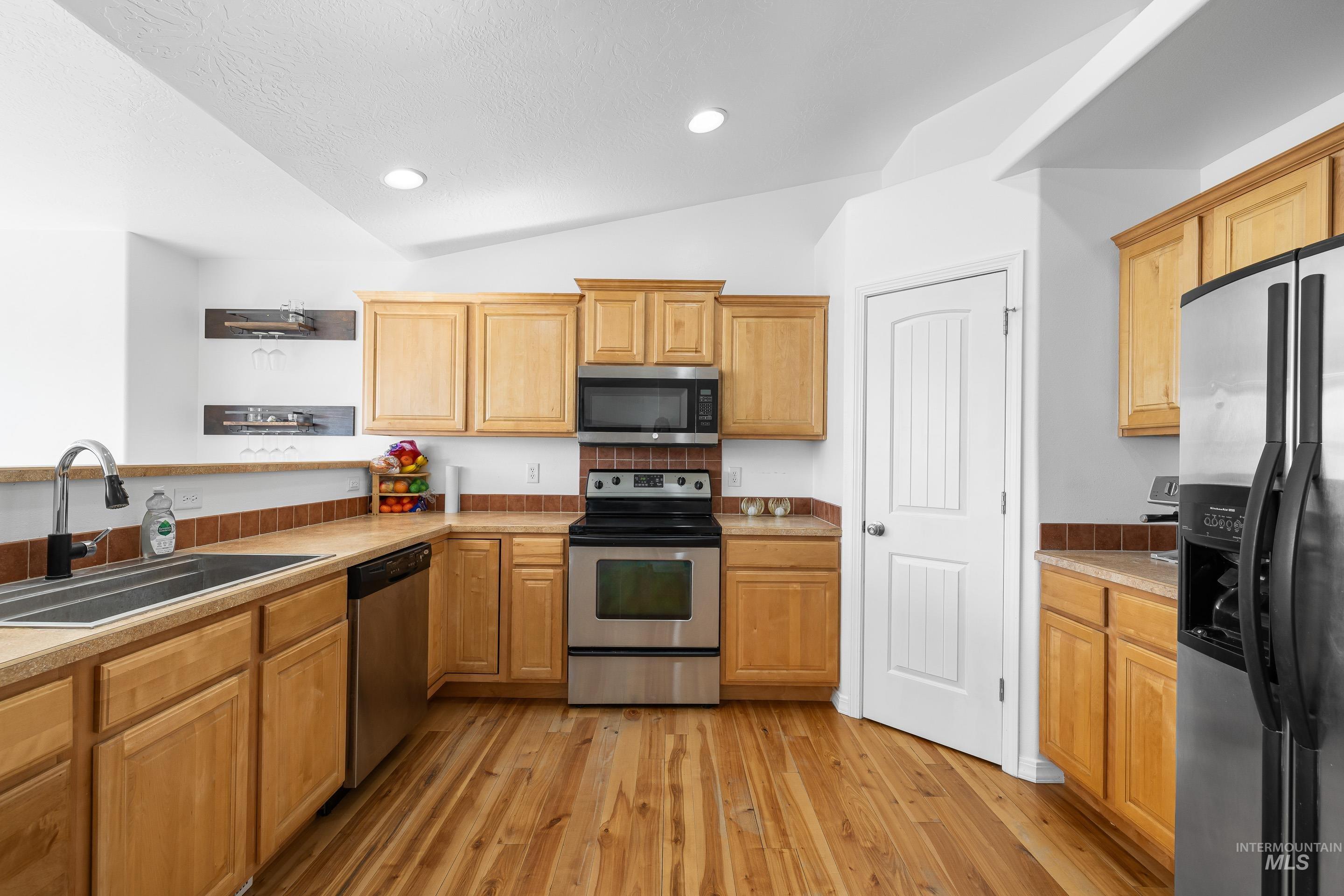 215 Northeast Rosa Court Mountain Home, ID 83647 - Photo 13 of 39 Kitchen featuring stainless steel appliances, lofted ceiling, light countertops, light wood finished floors, and recessed lighting