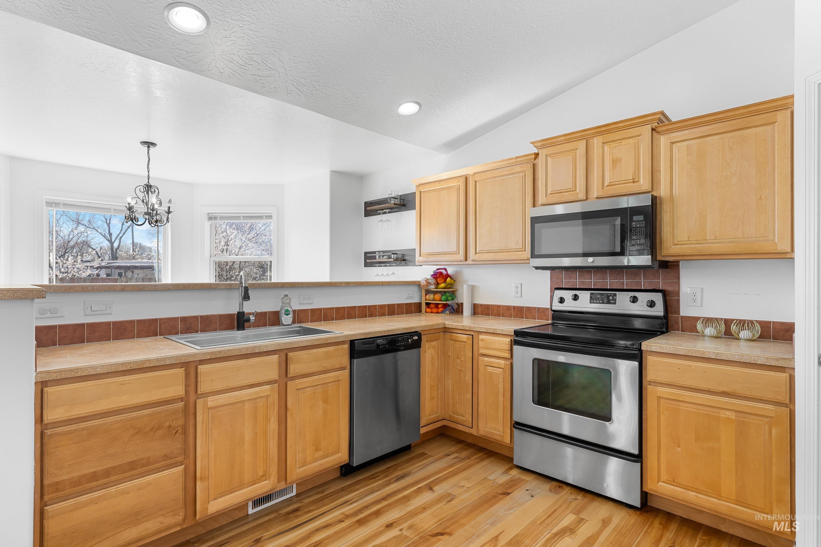 215 Northeast Rosa Court Mountain Home, ID 83647 - Photo 14 of 39 Kitchen featuring stainless steel appliances, light countertops, a chandelier, light wood-style flooring, and lofted ceiling