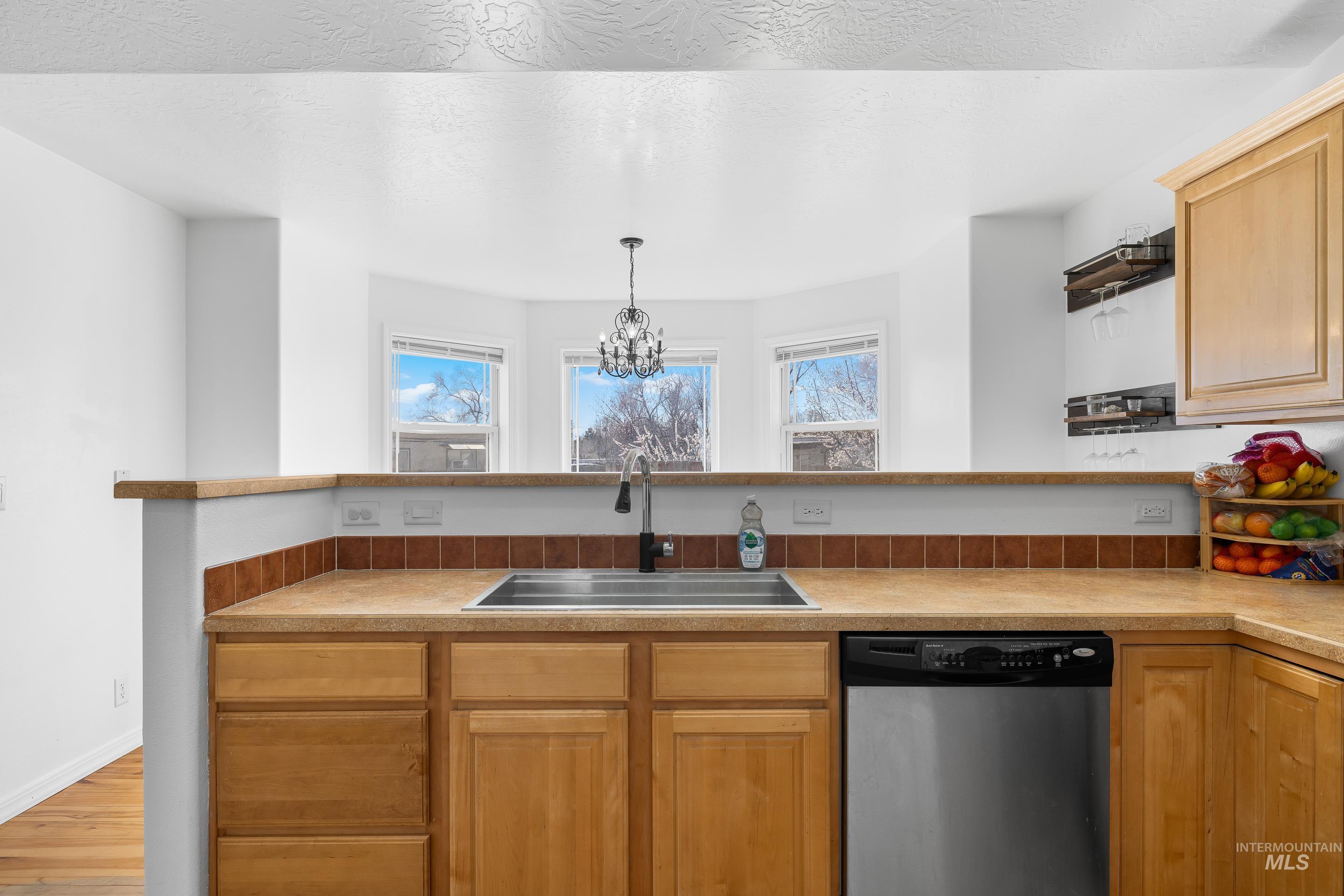 215 Northeast Rosa Court Mountain Home, ID 83647 - Photo 18 of 39 Kitchen featuring dishwasher, light countertops, a chandelier, and a peninsula