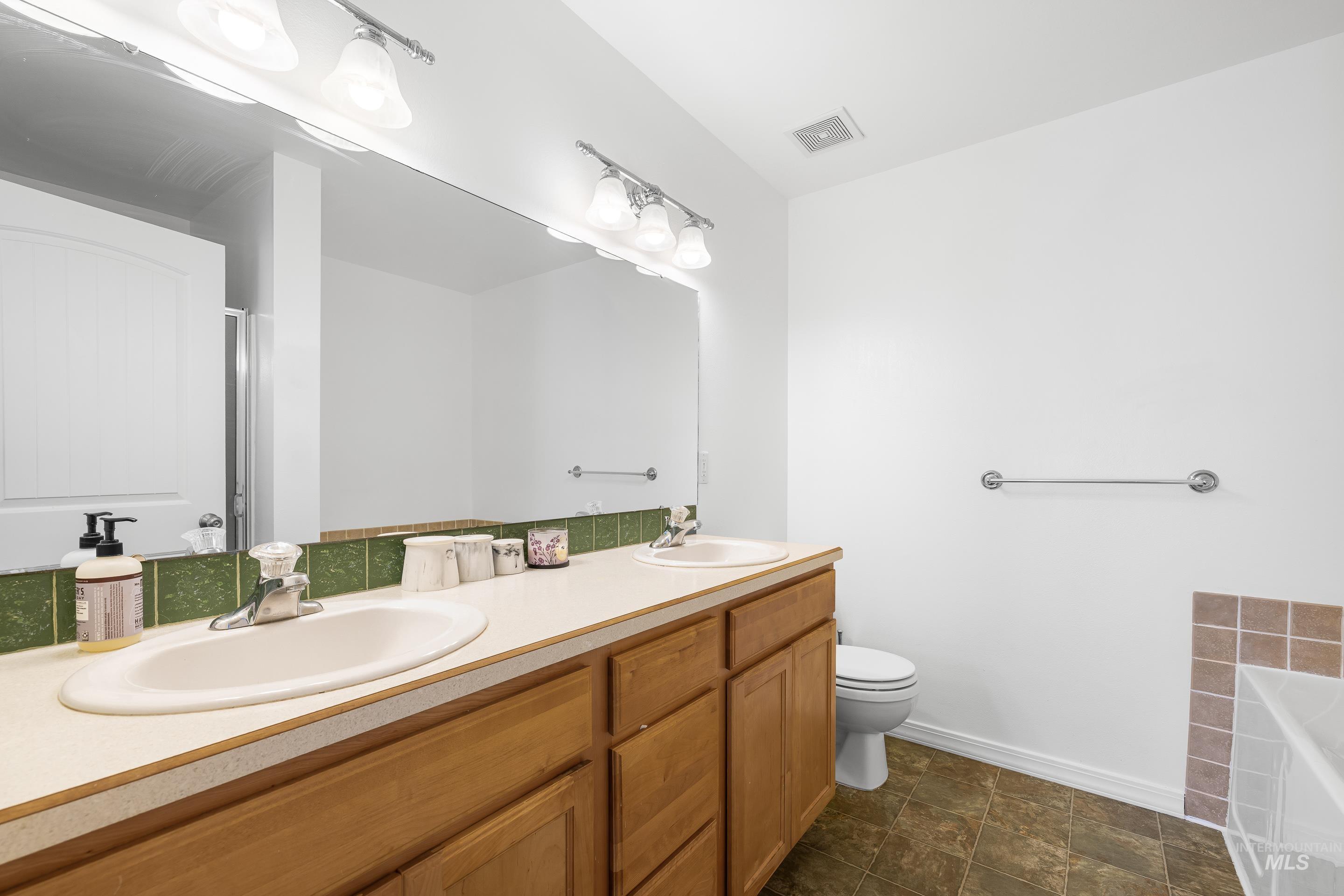 215 Northeast Rosa Court Mountain Home, ID 83647 - Photo 27 of 39 Bathroom featuring double vanity, a garden tub, a stall shower, and stone finish floors