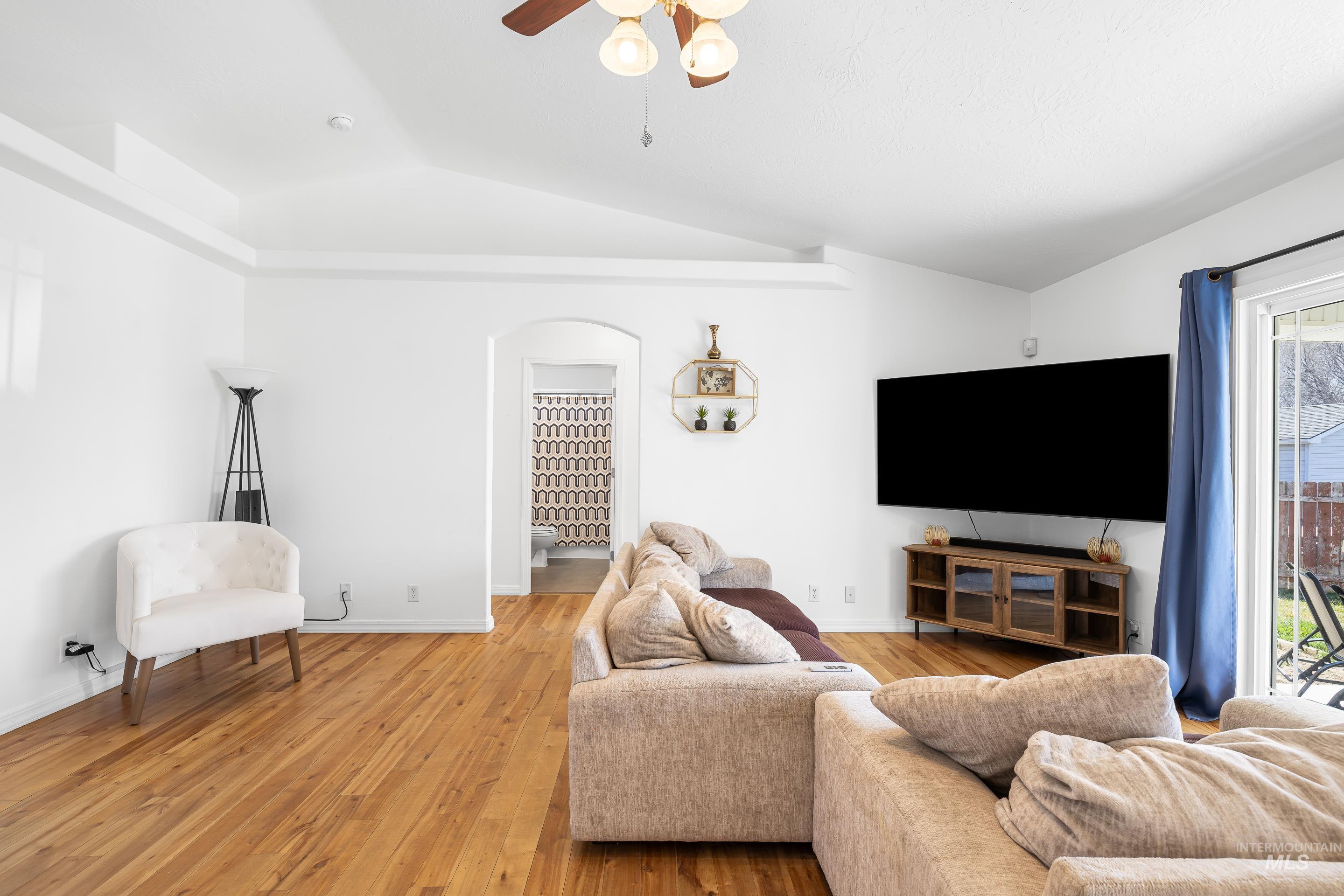 215 Northeast Rosa Court Mountain Home, ID 83647 - Photo 9 of 39 Living room with ceiling fan, arched walkways, light wood-type flooring, and vaulted ceiling