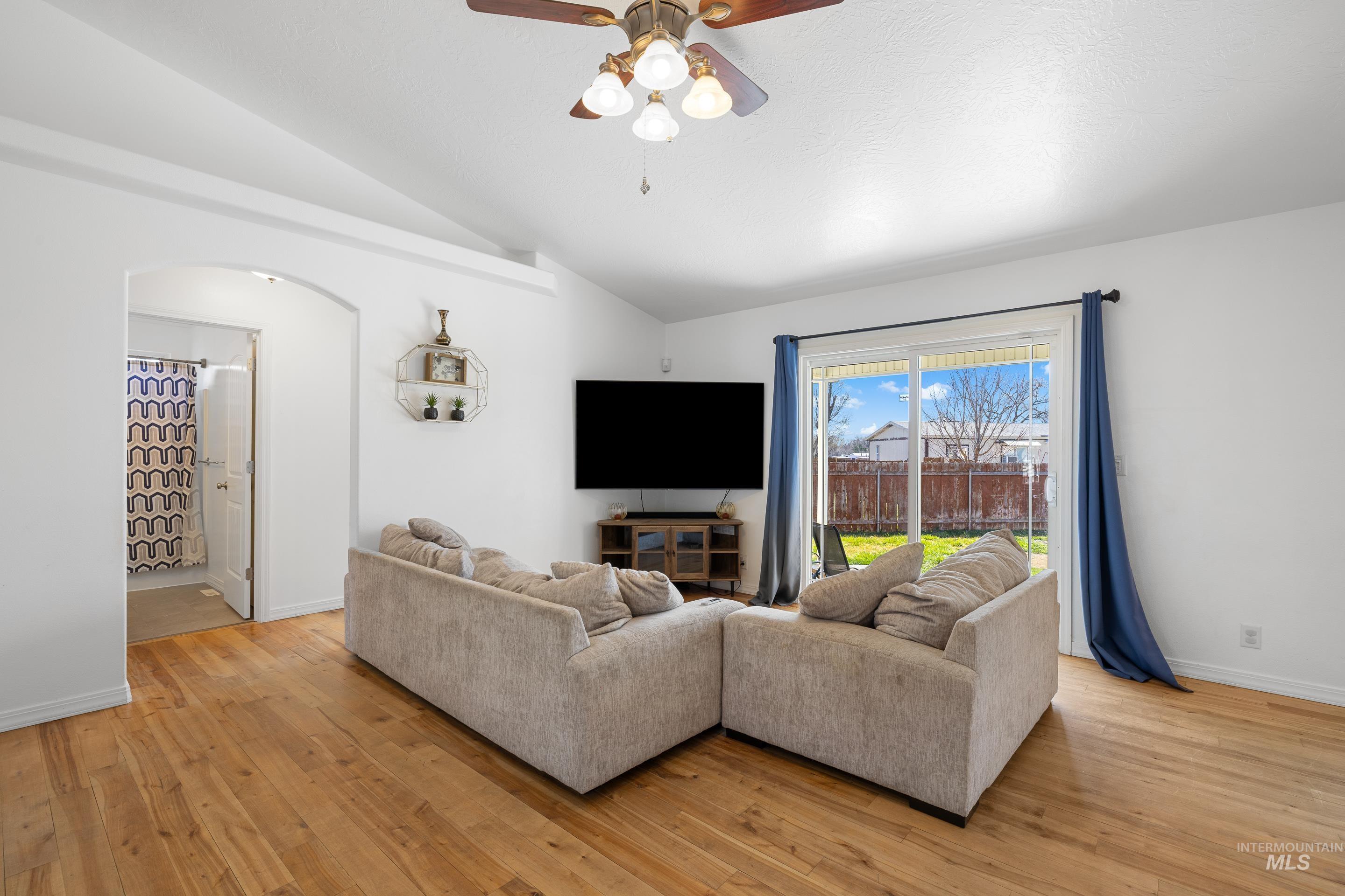 215 Northeast Rosa Court Mountain Home, ID 83647 - Photo 10 of 39 Living room with ceiling fan, arched walkways, light wood-style floors, and lofted ceiling