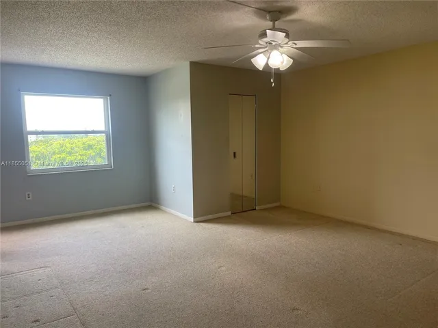 an empty room with a chandelier fan and windows