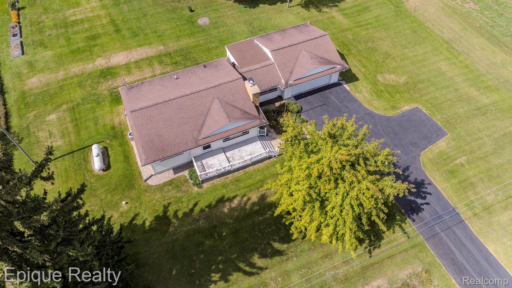 10091 North Genesee Road Mount Morris, MI 48458 - Photo 19 of 35 Expansive green lawn surrounding a residence with a multi-car driveway, attached garage, and a rear patio