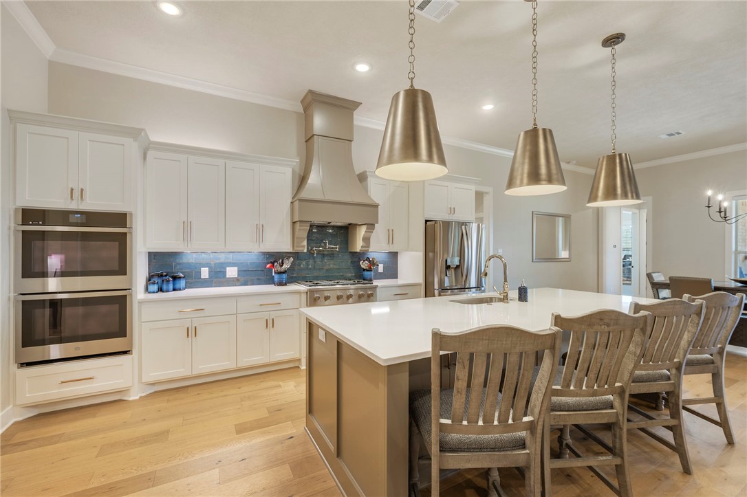 4804 Crystal Ridge Court College Station, TX 77845 - Photo 16 of 48 a kitchen with stainless steel appliances granite countertop a stove a sink a oven a kitchen island with chairs and white cabinets