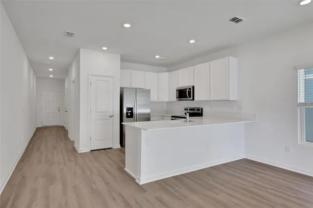 a view of kitchen with stainless steel appliances refrigerator stove microwave and cabinets