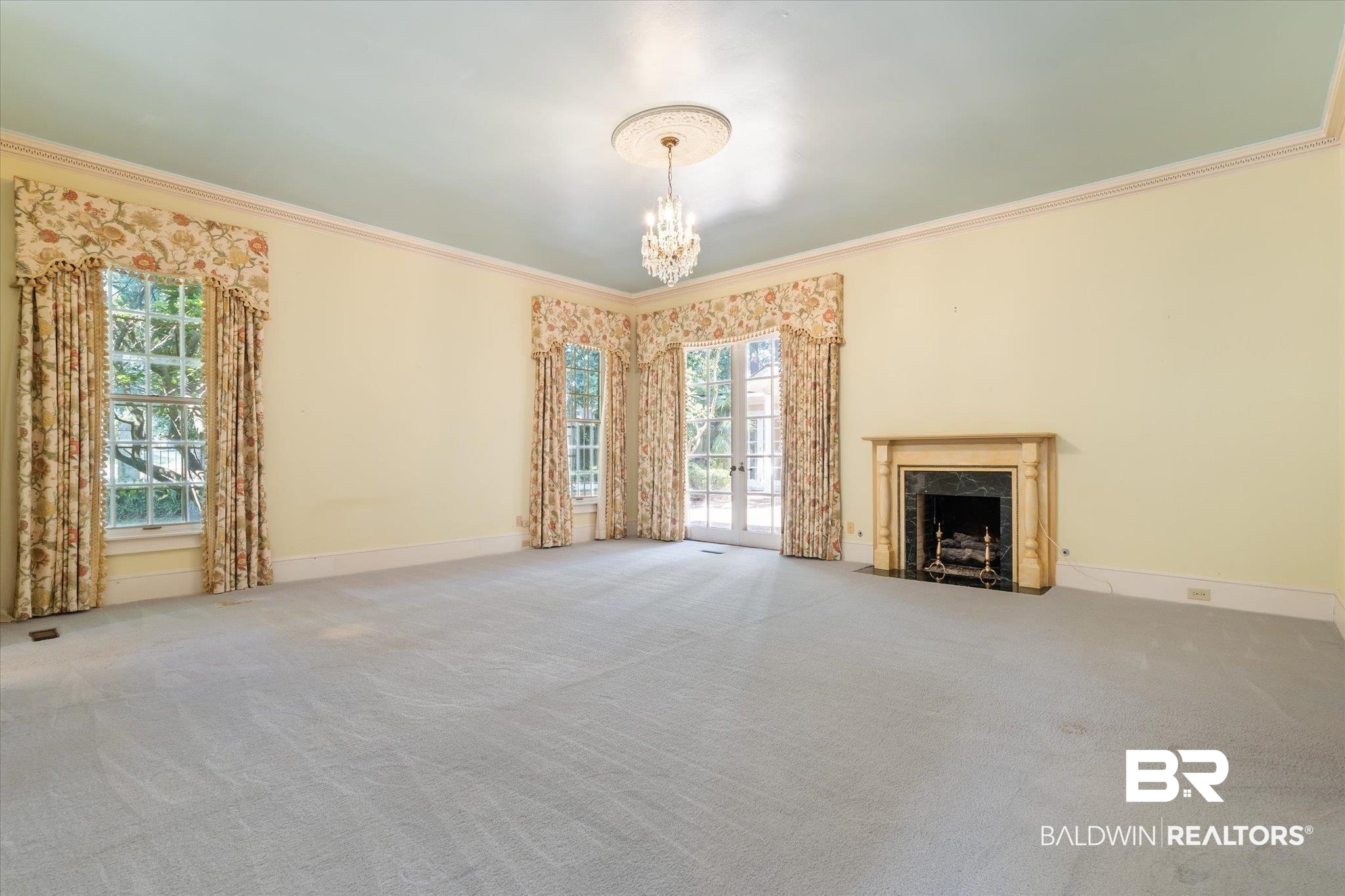 54 Turnin Lane Mobile, AL 36608 - Photo 17 of 35 Unfurnished living room with a notable chandelier, ornamental molding, a high end fireplace, and carpet