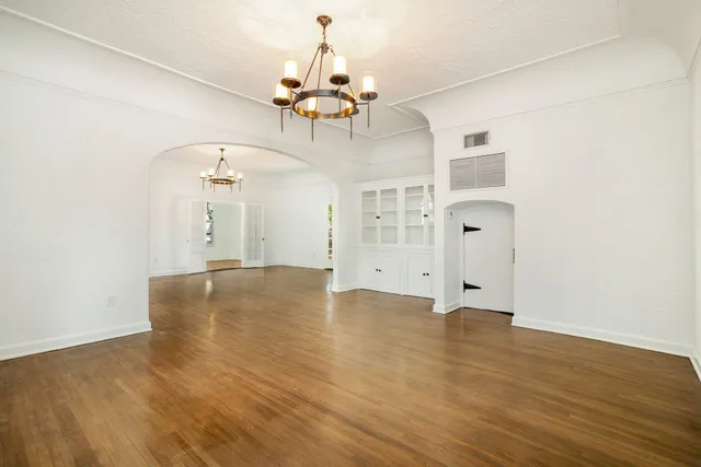 wooden floor in an empty room with a chandelier fan