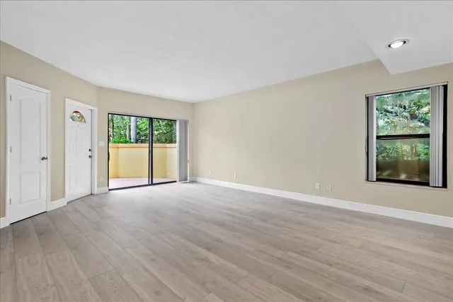 an empty room with wooden floor and a kitchen