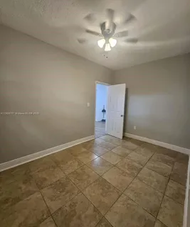 an empty room with a chandelier fan and windows