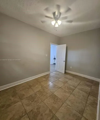 an empty room with a chandelier fan and windows