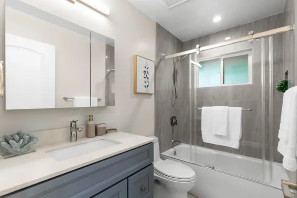 a bathroom with a granite countertop sink toilet a mirror a vanity and shower