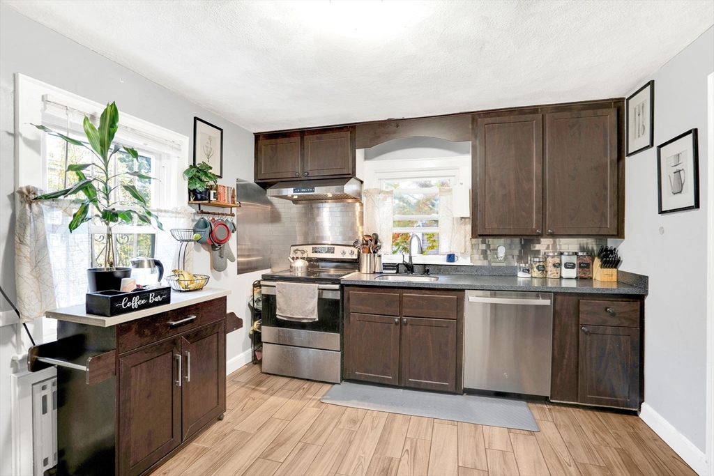 39 Range Road Boston, MA 02124 - Photo 5 of 25 a kitchen with stainless steel appliances granite countertop wooden cabinets a stove top oven a sink and dishwasher with wooden floor