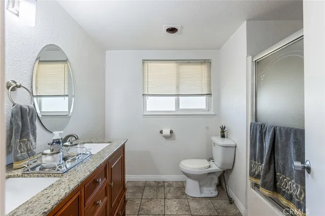 a bathroom with a granite countertop toilet a sink and a mirror