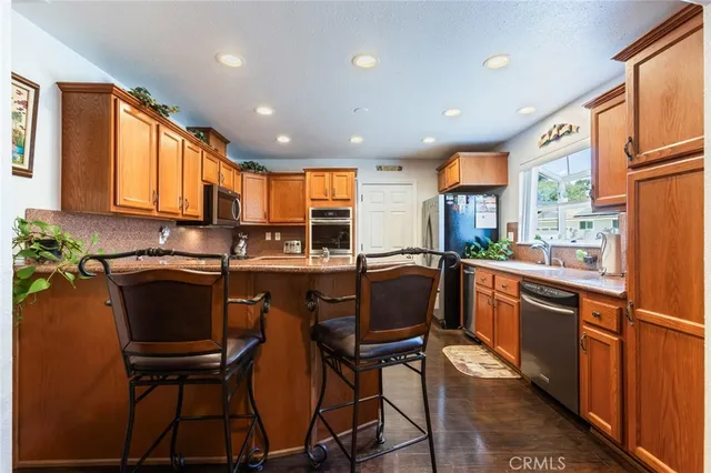 a kitchen with stainless steel appliances granite countertop sink refrigerator and cabinets