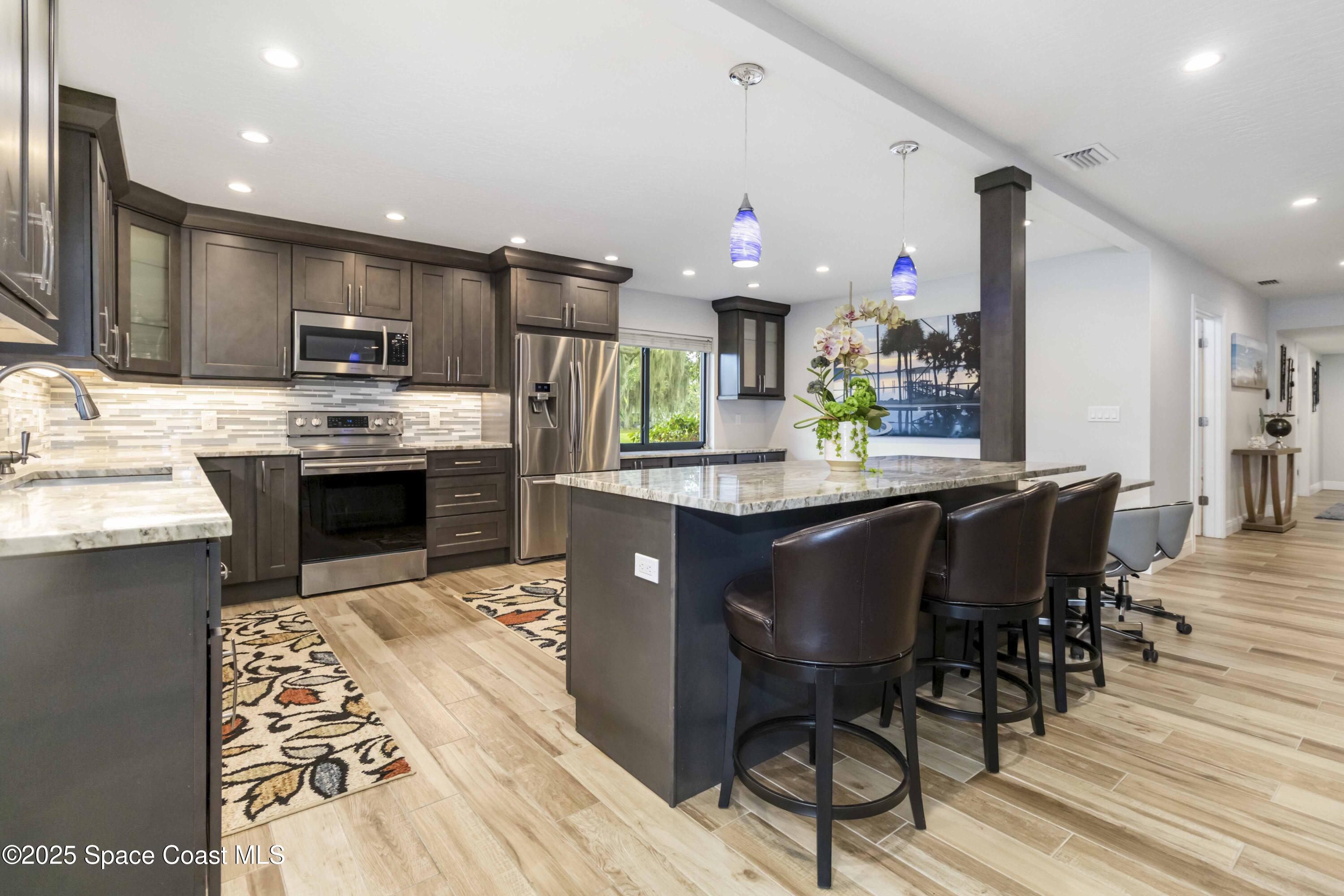 110 Barnacle Place Rockledge, FL 32955 - Photo 39 of 73 a kitchen with stainless steel appliances granite countertop a stove top oven a sink dishwasher and a dining table with wooden floor
