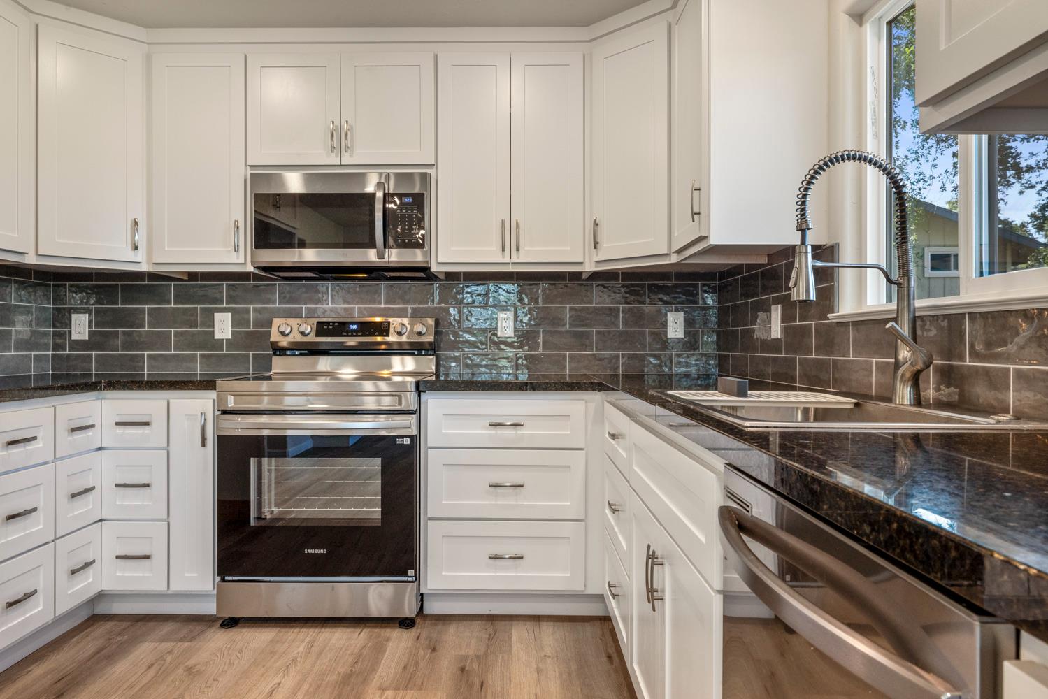 2324 Quail Hill Road Copperopolis, CA 95228 - Photo 12 of 52 a kitchen with white cabinets and stainless steel appliances