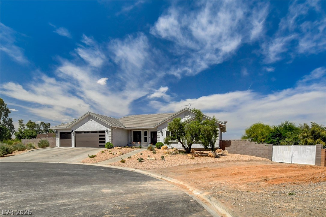 4362 Thistle Street Logandale, NV 89021 - Photo 3 of 99 A desert oasis with a paved drive leading to an attached three-car garage, surrounded by drought-tolerant landscaping.
