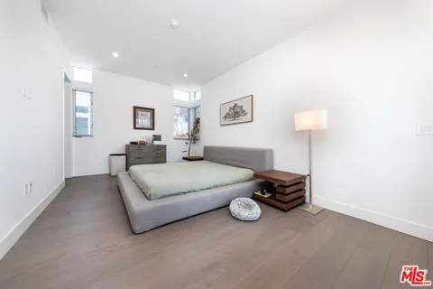 a bedroom with a bed wall painting and a window