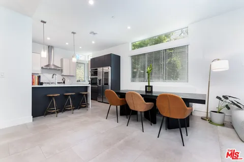 a dining room with stainless steel appliances kitchen island granite countertop furniture and a large window