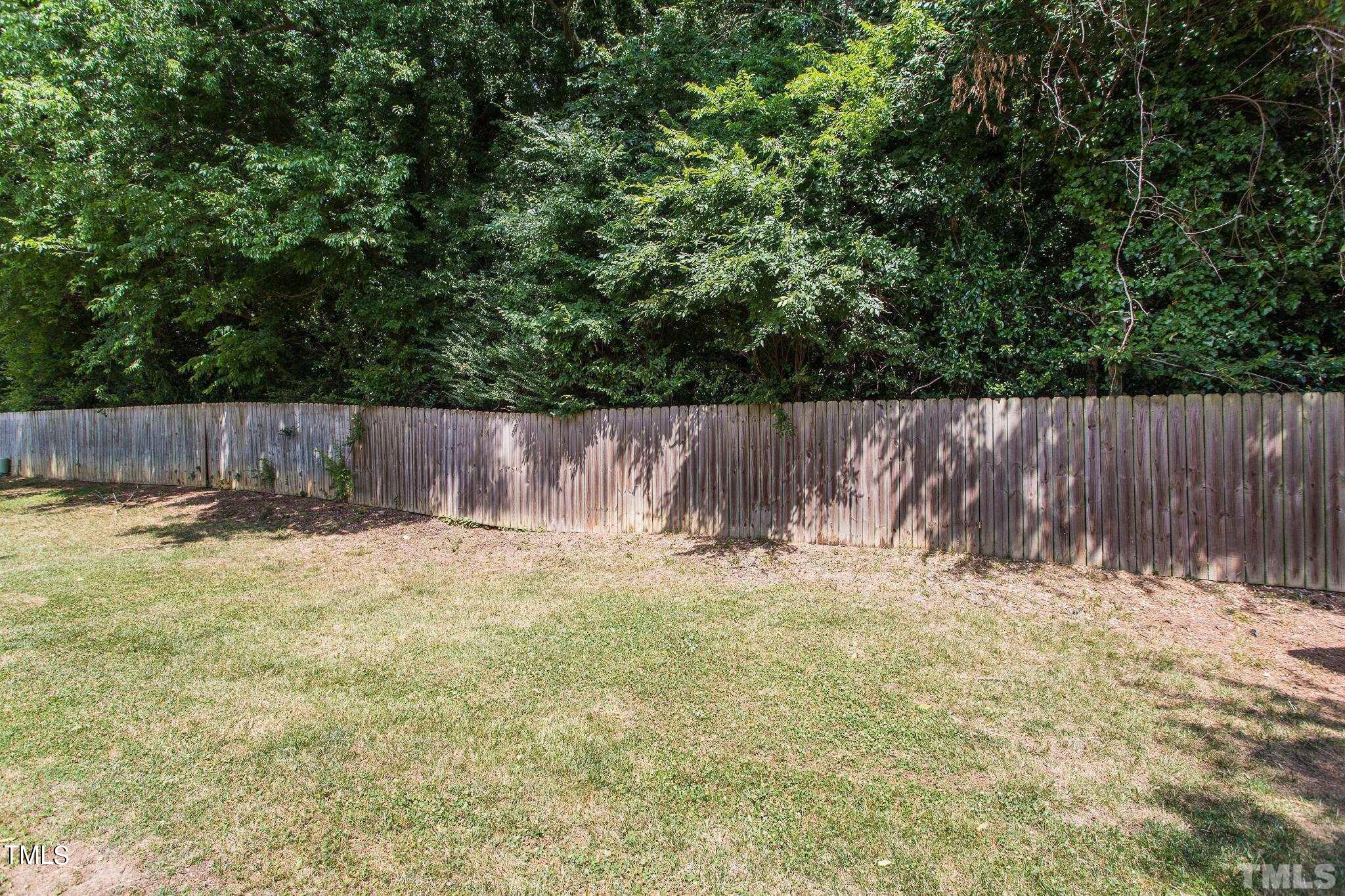 4424 Roller Court Raleigh, NC 27604 - Photo 4 of 19 a view of a backyard with large tree and wooden fence