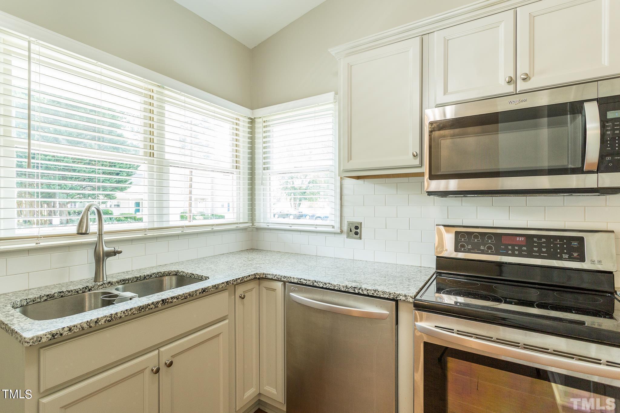 4424 Roller Court Raleigh, NC 27604 - Photo 7 of 19 a kitchen with granite countertop a sink stainless steel appliances white cabinets and a window