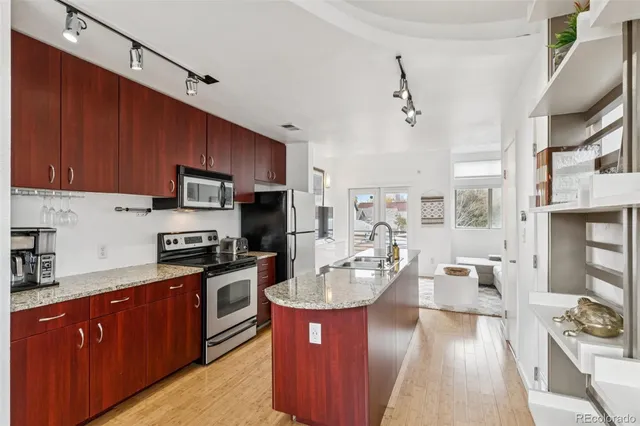 a kitchen with stainless steel appliances kitchen island granite countertop a sink dishwasher stove top oven and cabinets with wooden floor