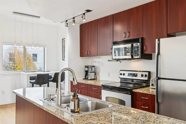 a kitchen with granite countertop a sink stainless steel appliances and cabinets